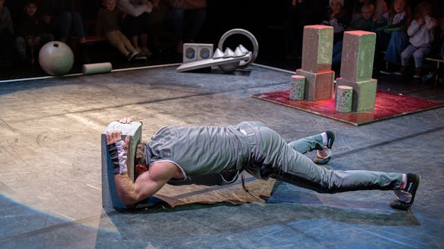 Een performer voert een acrobatische act uit met een blok op het podium.