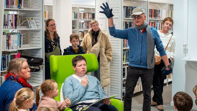 Voorleesouder beeldt levendig uit wat er in het verhaal gebeurt, kindjes en ouders luisteren aandachtig mee.