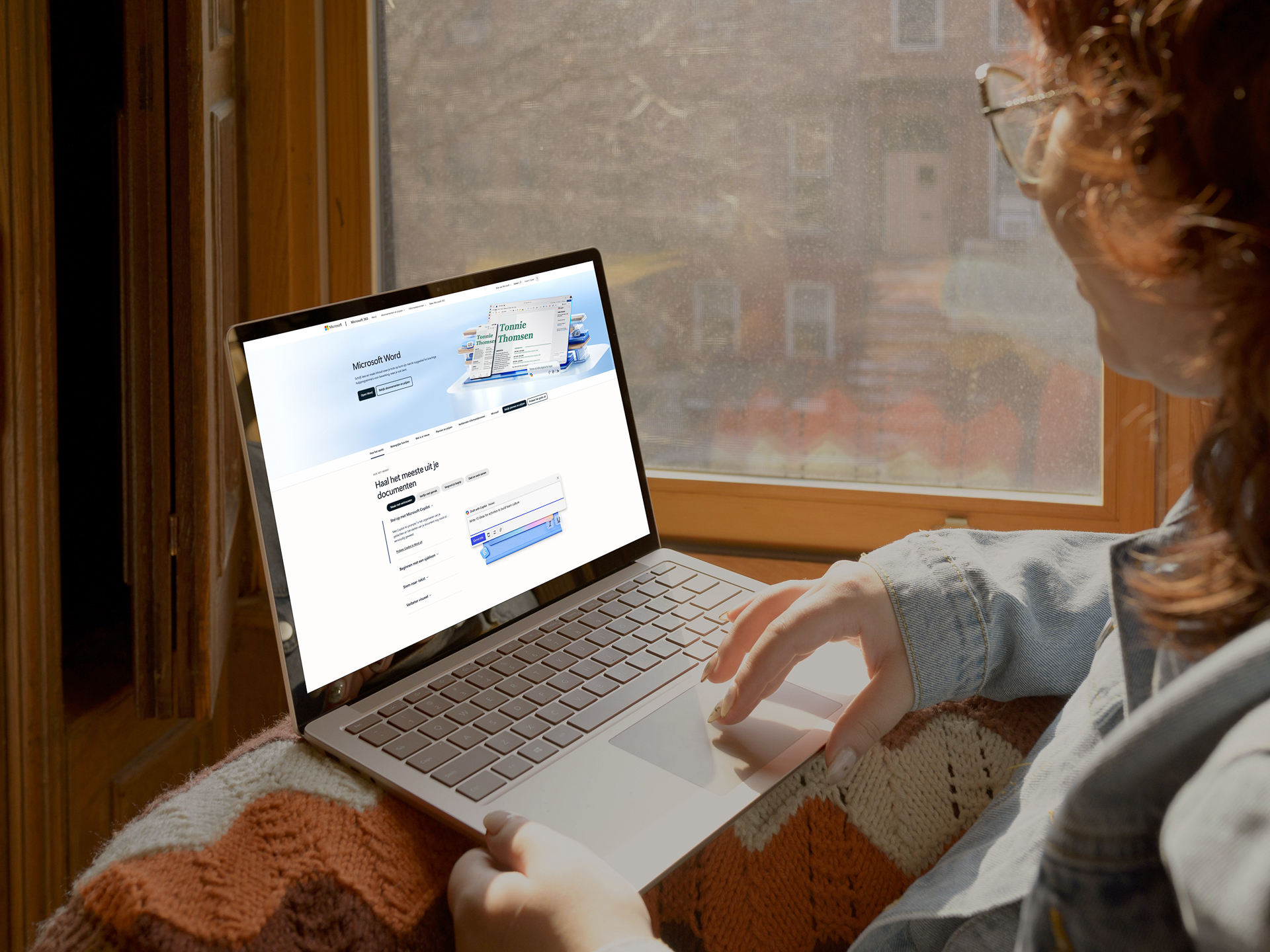 Dame met een bril met een laptop op de schoot, de geopende pagina toont starten met Microsoft Word