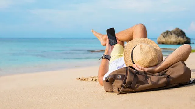 Persoon ligt op het strand en gebruikt gsm