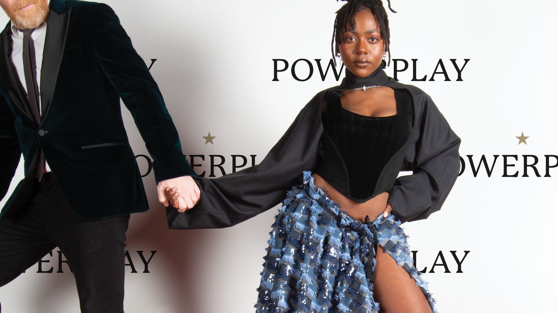 Man en vrouw op rode loper voor achterwand met 'powerplay'; man trekt vrouw weg.