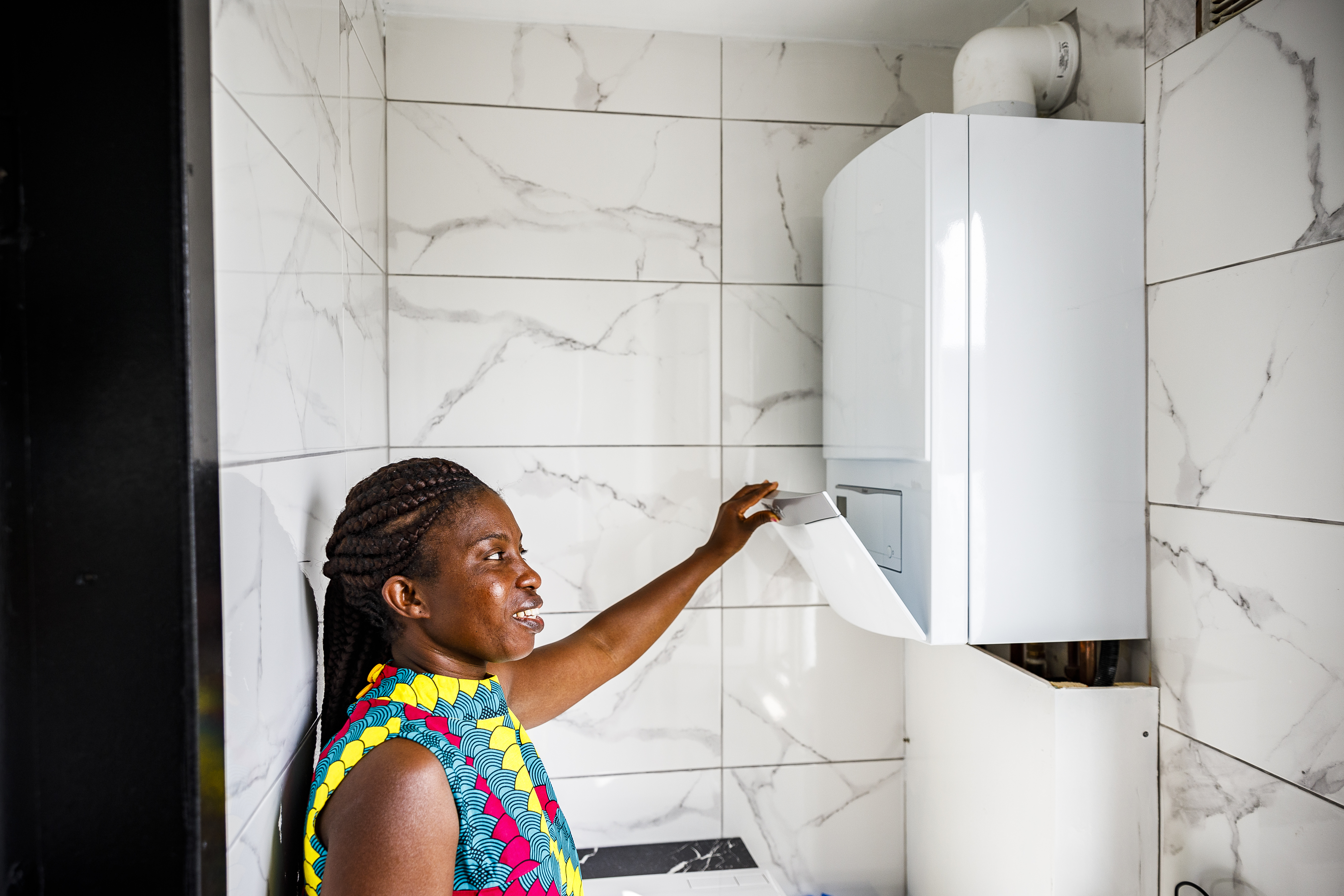 Vrouw aan een doorstroomboiler in een badkamer
