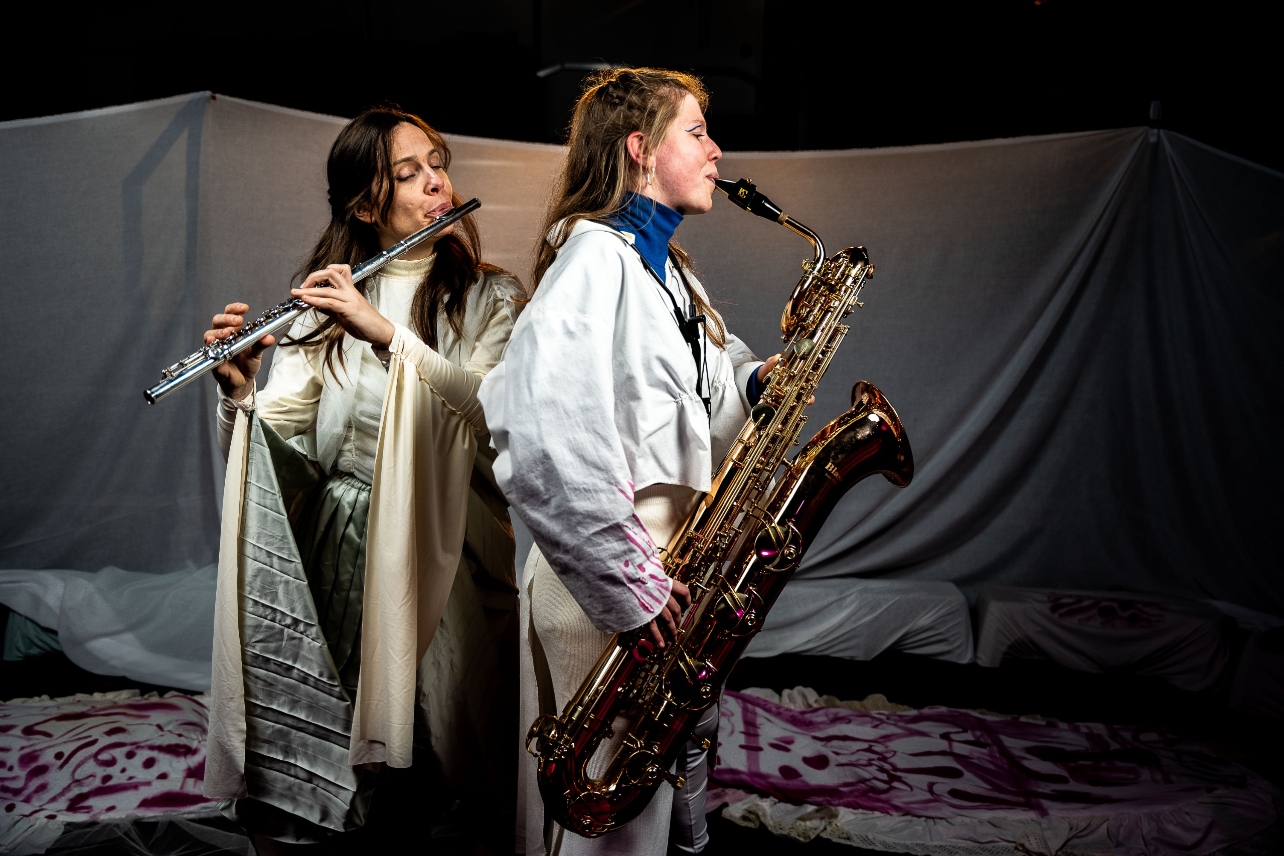 Twee muzikanten spelen samen: een fluitiste en een saxofoniste.