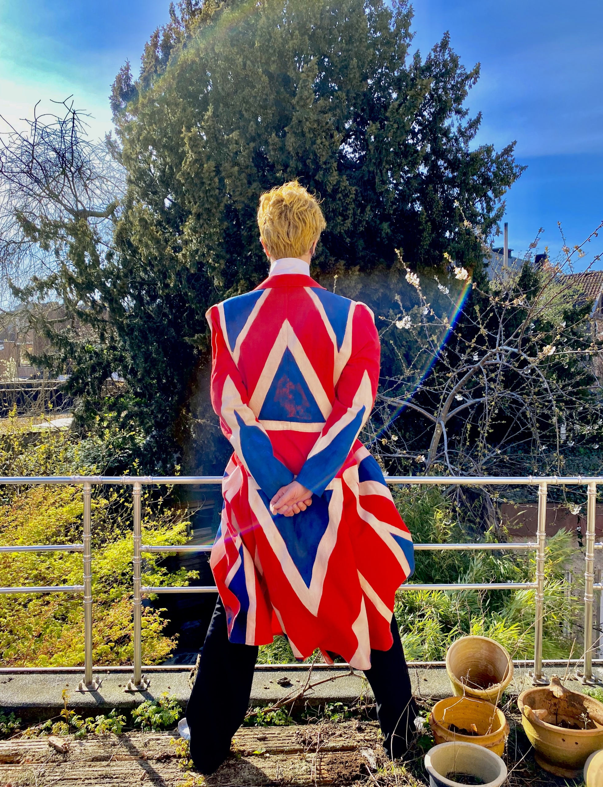 Persoon in een opvallende jas met de Britse vlag, staand met de rug naar de camera.