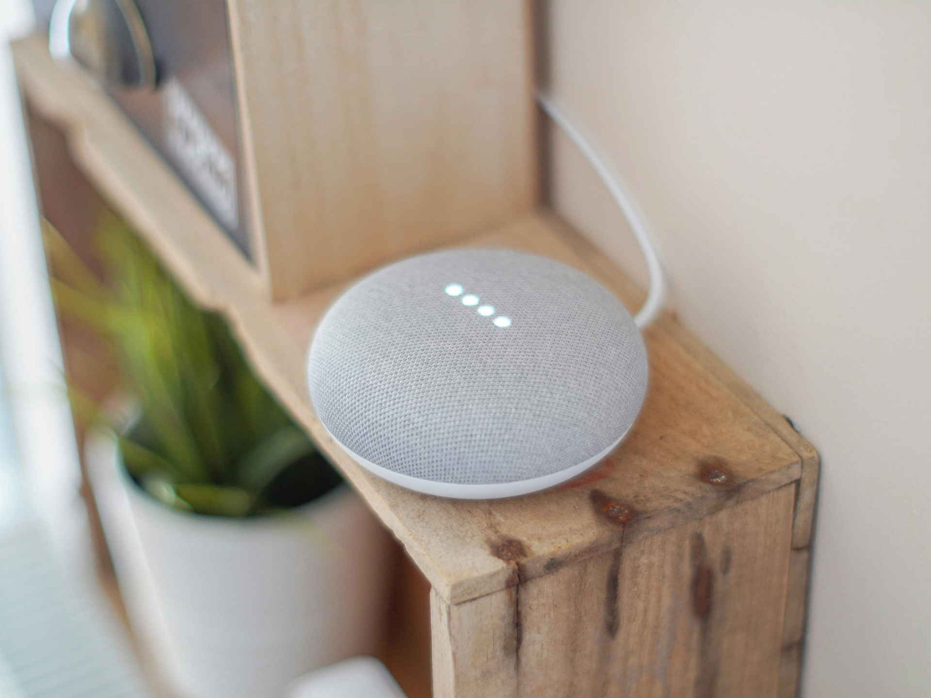 Een Google home slimme speaker die op een houten kastje staat
