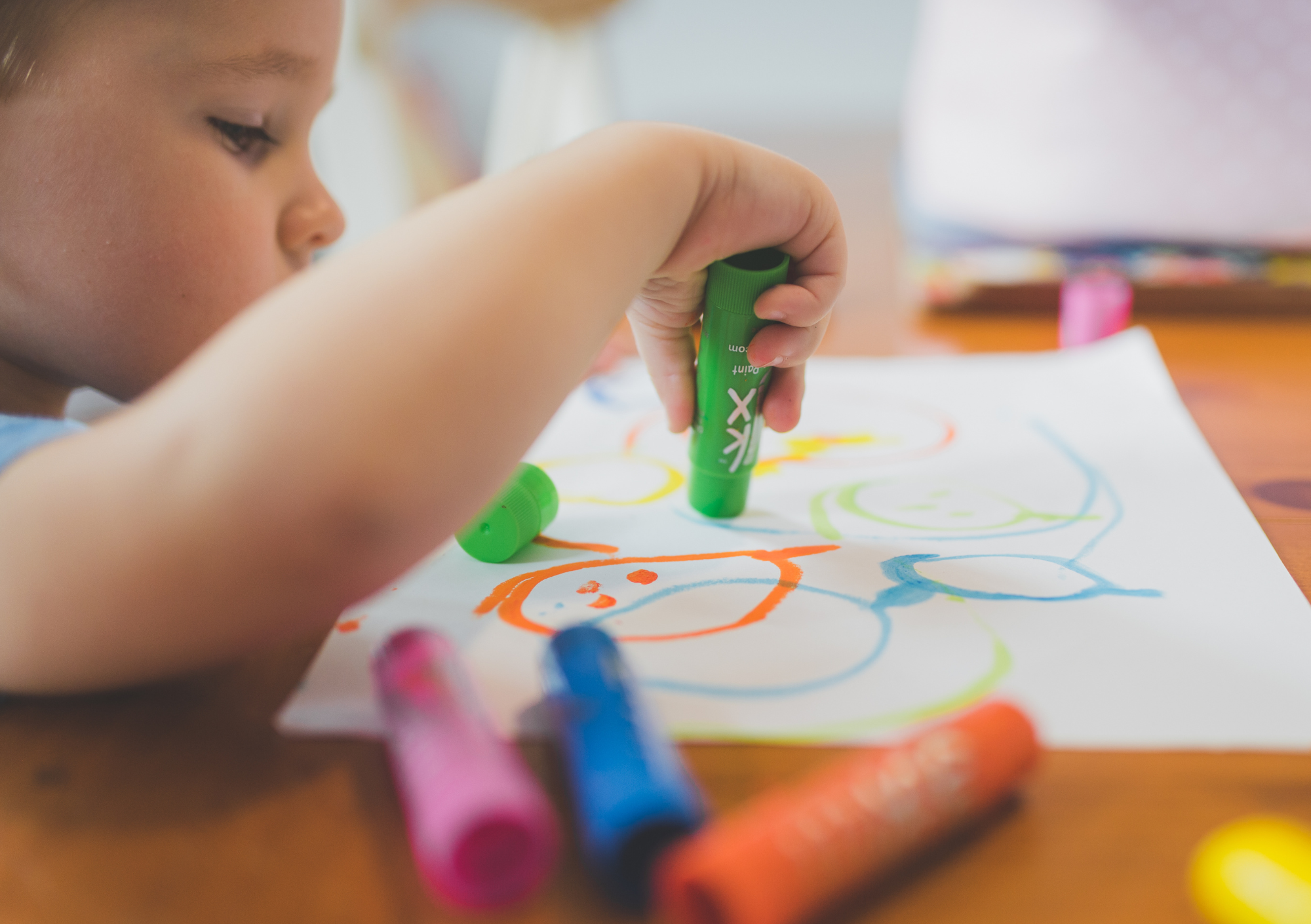 Kind tekent met wasco's op papier