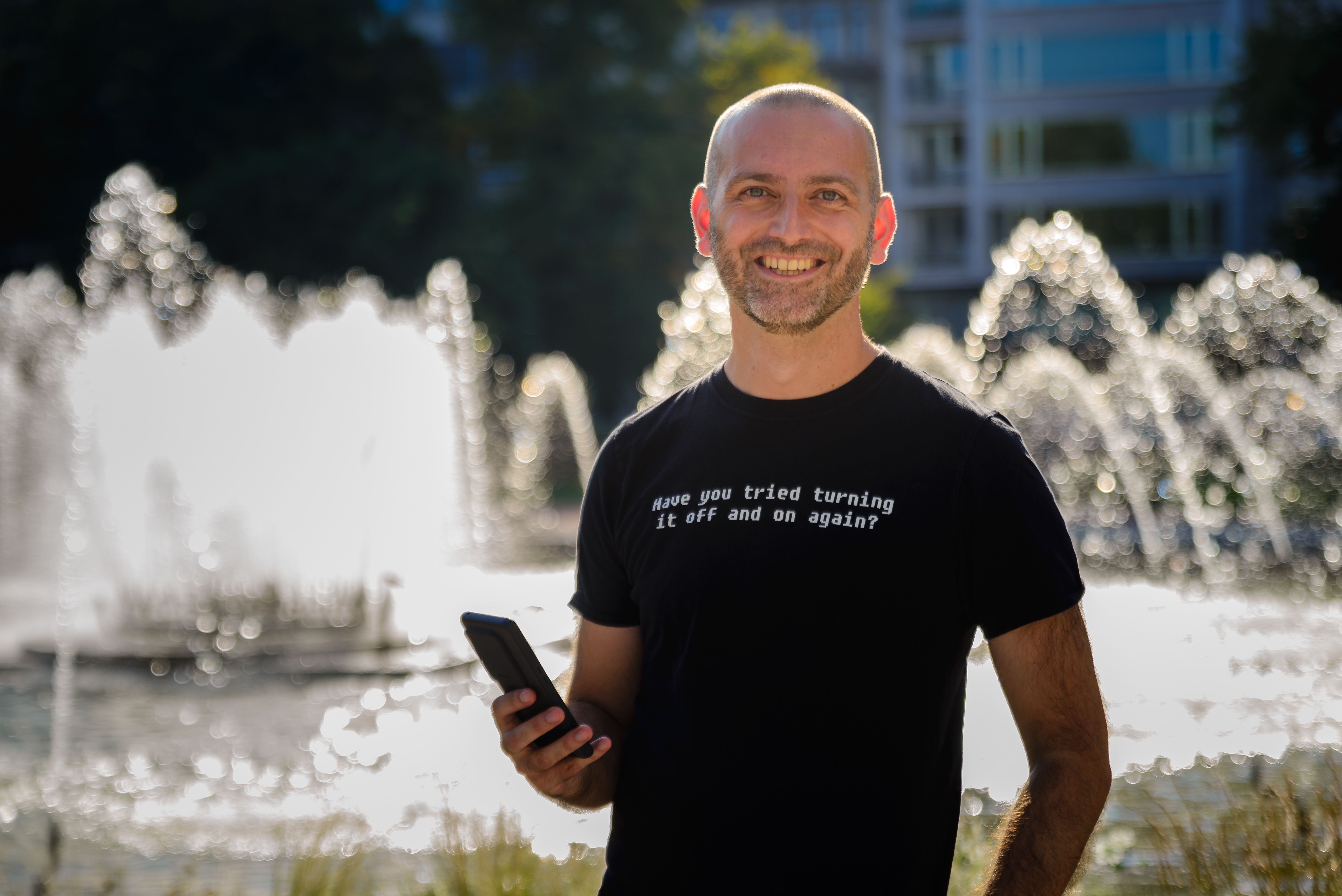 Foto van Kristof D'Hanens, poserend met een smartphone voor een fontein