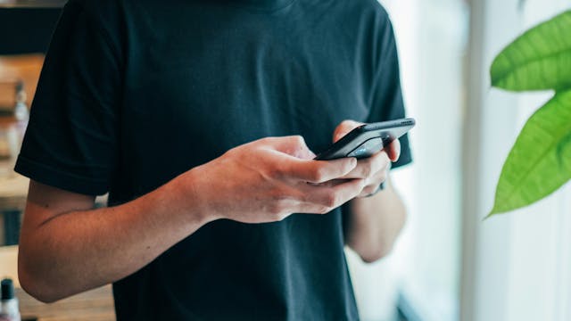 persoon met zwarte t-shirt die iets intikt op een smartphone