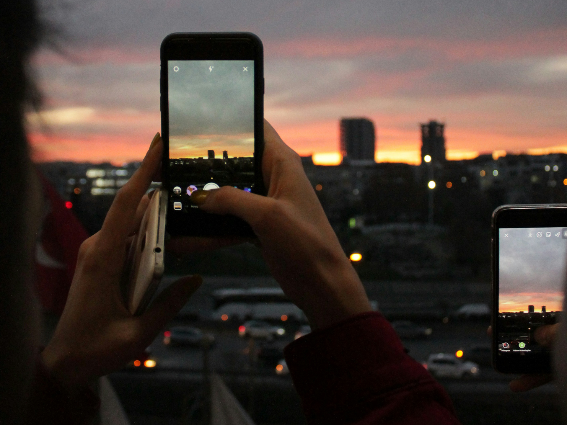 Persoon die bij zonsondergang een foto neemt met de smartphone van de hemel en skyline in de verte
