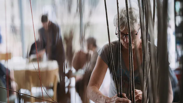 Iemand vlecht met wilgentakken een stuk van een huifkar