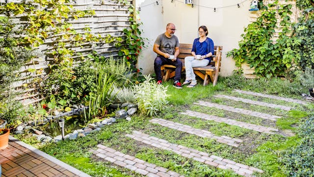 Koppel zit op een bank in een kleine stadstuin.
