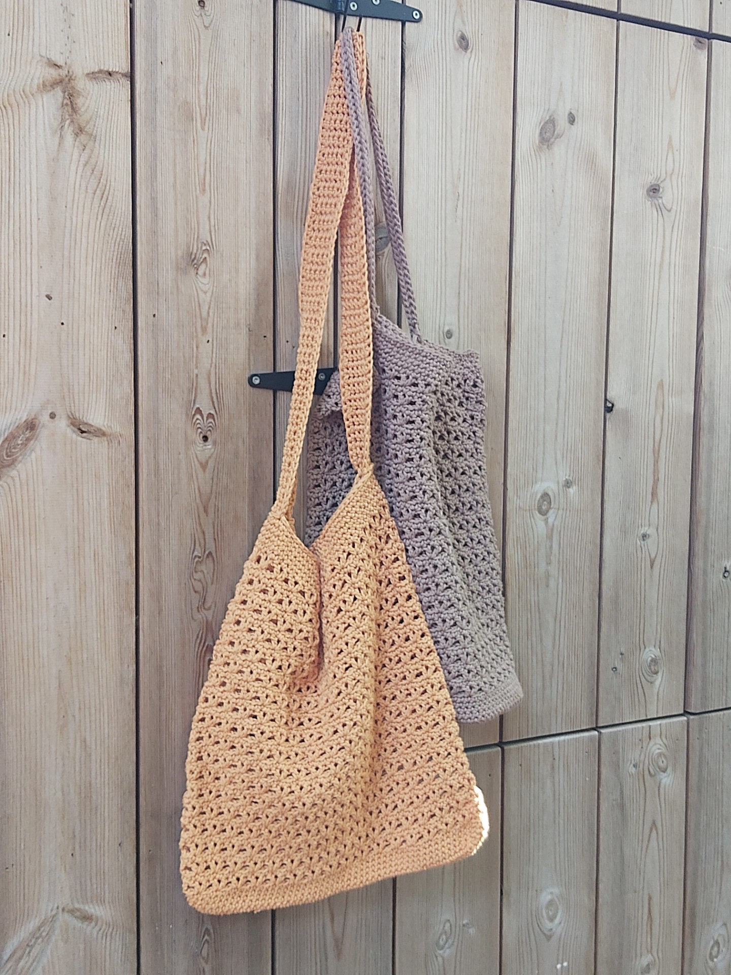 2 gehaakte zomertassen aan een houten muur