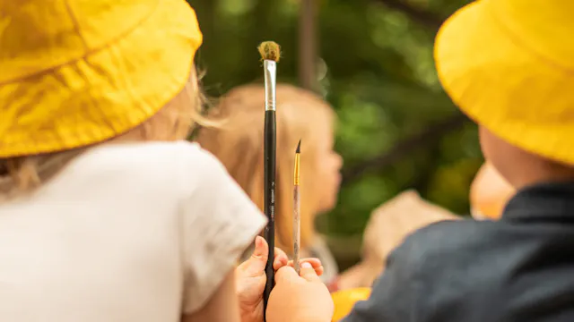 Twee kindjes met een penseel en geel hoedje