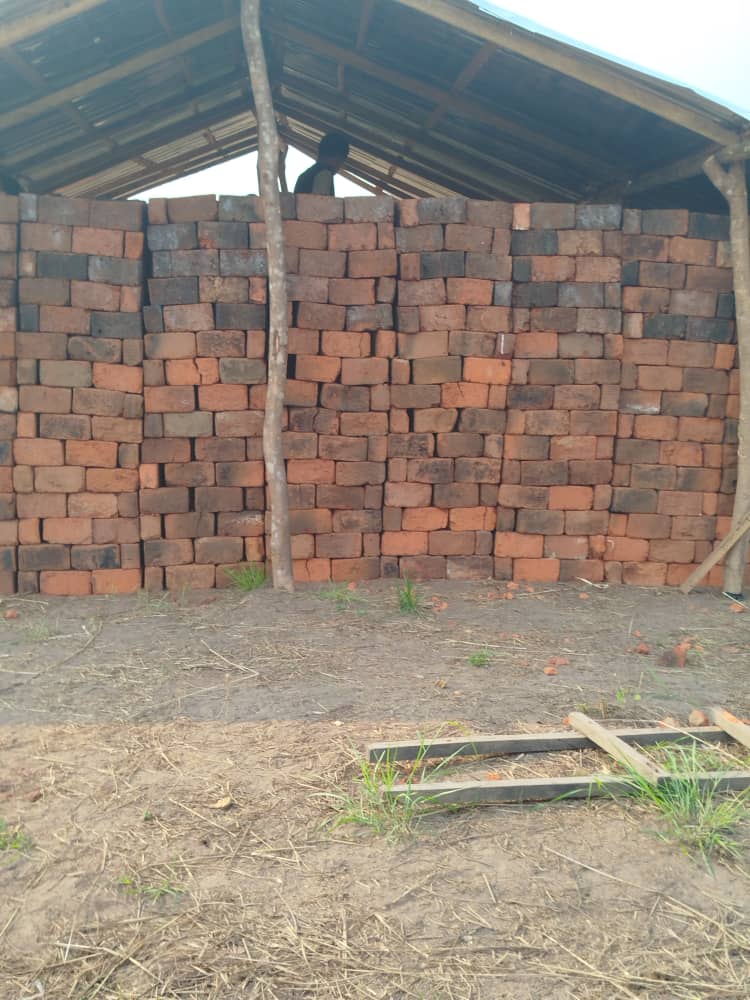 Het afdak is gevuld met duizenden artisanaal gebakken bakstenen. Ze staan klaar op het bouwterrein.