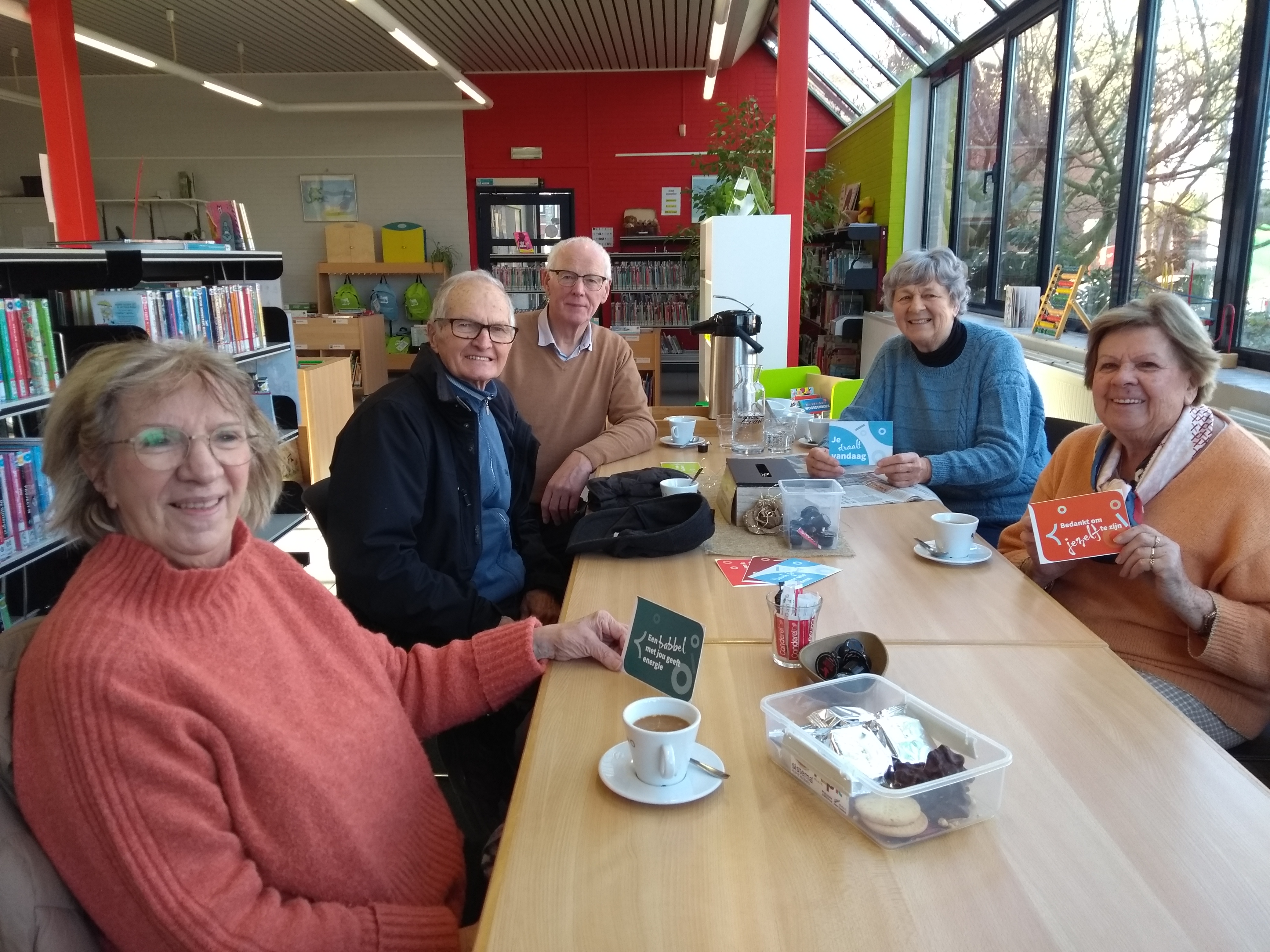 Mensen geven een complimentenkaart aan elkaar of zichzelf tijdens een gezellige babbel.