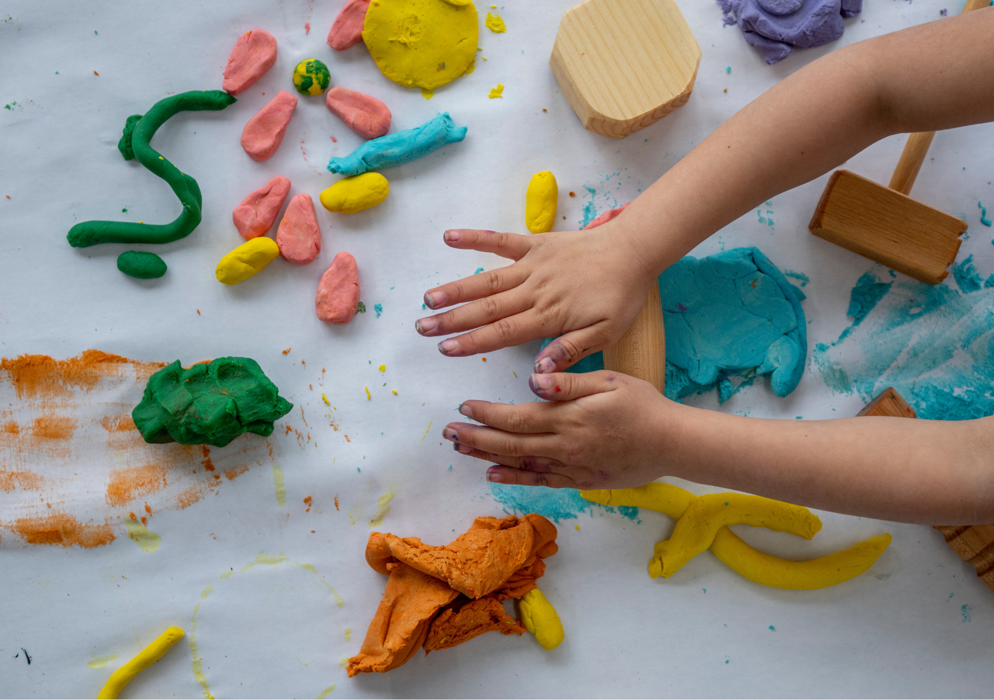 Twee kinderhanden bewerken kleurrijke klei